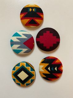 four buttons with different designs on them sitting next to each other in the shape of an arrow