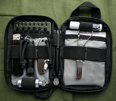 an open tool bag with tools in it on a green surface, showing the contents inside