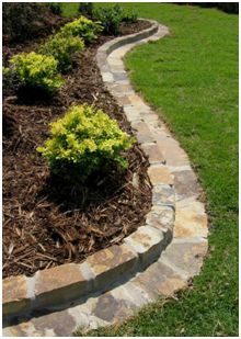 a stone path in the middle of a lawn with yellow flowers on it and green grass