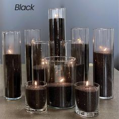 there are many candles in glass vases on the table