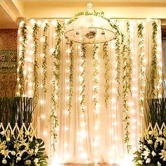 wedding stage decoration with white flowers and greenery hanging from the ceiling, surrounded by fairy lights