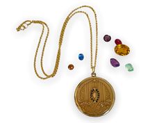 "Description: A large and lovely antique round Art Deco era monogrammed gold filled photo locket on a new 14K gold filled chain.  The front of this locket made by the SB Company, features a central raised oval shape surrounded by a total of 14 \"paste\" stones. The stones that were probably once clear have darkened with age. There are 7 in paste gems on each side of the central oval. At the top and at the bottom of this oval shape is a raised fleur de lis. There are a total of 6 raised vertical