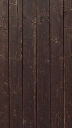 an orange cat is sitting on the floor next to a brown wall with wood planks