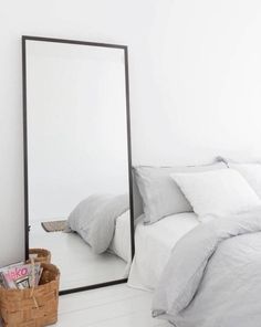 a bedroom with a large mirror on the wall next to a bed and a basket