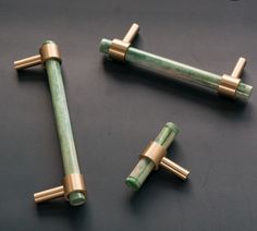 three brass and green handles on a black surface