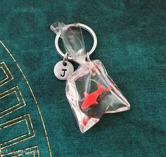 a keychain with a red fish in it sitting on a green surface next to a blue rug