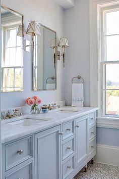 a white bathroom with two sinks and mirrors on the wall next to a large window