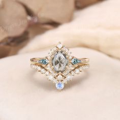 a diamond ring with blue and white stones on it's sides, sitting on top of a pillow