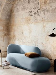 a blue couch sitting in front of a stone wall