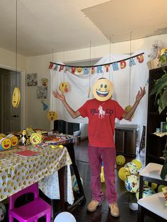 a young boy standing in front of a table with balloons and decorations on the wall