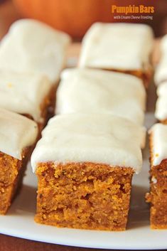 several pieces of carrot cake with frosting on a white plate, ready to be eaten