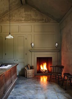 an empty room with a fire place in the center and two chairs next to it