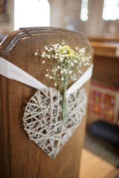 a bouquet of baby's breath tied to the back of a wooden church pew