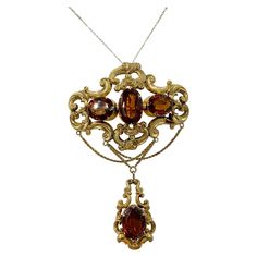 This is a spectacular antique Victorian - Belle Epoque Pendant Brooch with 30 Carats of Magnificent Citrine gems set in a stunning open work acanthus scroll swag design in 10-12 Karat Gold. The pendant is a monumental size, 4 1/8 inches long, which creates a dramatic statement jewel of the highest quality. The top portion has three oval faceted natural mined citrines. The bottom pendant portion is set with a fourth oval citrine. The bottom portion is detachable. The entire jewel has the beautiful repousse gold work with wonderful engraved details that we associate with the fine Belle Epoque jewels. The citrine gems are all collet set and open backed in order to let the maximum amount of light through. The gold chains creating the swag design are a wonderful addition. The pendant also has a Acanthus Scroll, Victorian Pendant Necklace, Swag Design, Antique Necklaces Design, Victorian Pendants, Pendant Brooch, Jewellery Vintage, Snake Pendant, Beaded Jewelry Tutorials