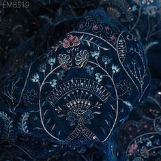 a close up view of an intricately designed blue cloth with flowers and leaves on it