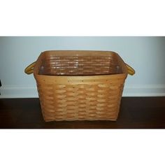 a brown wicker basket sitting on top of a wooden floor next to a wall