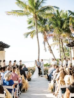 a bride and groom standing at the end of their wedding ceremony in front of palm trees