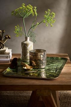 there is a vase with flowers in it on the table next to two cups and a book