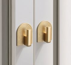 two gold door handles on white doors with arch shaped knobs in the shape of a rainbow