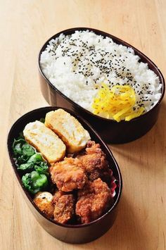 two containers filled with rice, meat and veggies on a wooden table next to each other