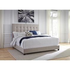 a white bed sitting in a bedroom on top of a hard wood floor next to a window