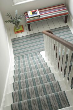 the stairs are decorated with blue and white striped rugs, along with a bench