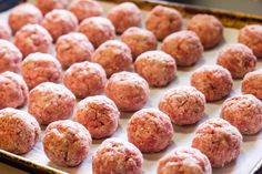 raw meatballs on a baking sheet ready to be cooked