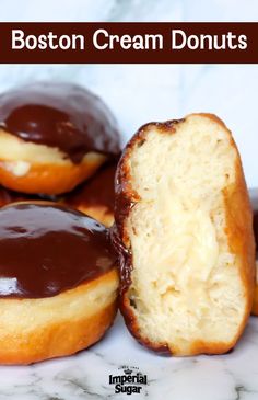 three boston cream donuts with chocolate frosting on top and one half eaten in the middle