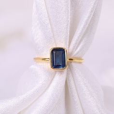 a gold ring with a blue stone on it sitting on top of a white cloth