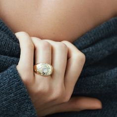 a woman's hand with a gold ring on her finger and a blue sweater