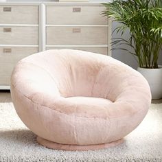 a pink bean bag chair sitting on top of a white rug in front of a dresser