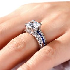 a woman's hand with a diamond and blue sapphire engagement ring on her finger