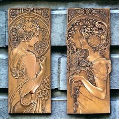 two gold plaques depicting women with flowers on the side of a brick wall in front of a