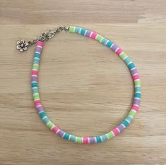 a multicolored beaded bracelet with a flower charm on a wooden table top