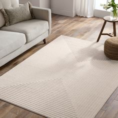 a living room with a couch, chair and rug on the wooden floor next to a window