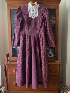 An original and highly collectible, 1980s Gunne Sax prairie dress by Jessica McClintock dress. It has a high mock neck with lace, and a subtle paisley print, complemented with ticking stripes through the middle. It is in excellent condition, I can't find any flaws, but please note that it's vintage, and may show some gentle use.  The neck is approximately 14" around, so please measure your own neck to ensure it will fit. It does have two buttons at the back of the neck that could be left undone for slightly more room, especially if your hair is down, and able to cover that area.  It has shoulder pads, and a 23" long zipper in the back, for ease of taking on and off. Material is 50% Polyester, 50% cotton. Hand wash cold. No chlorine bleach. Line dry. Cool iron.  With its pleating, I believe Fitted Vintage Dress With Lace Trim For Fall, Vintage Long Sleeve Prairie Dress For Formal Events, Vintage Long Sleeve Prairie Dress For Formal Occasions, Vintage Long Sleeve Dress With Fitted Bodice, Vintage Dresses With Lace Trim For Fall, Fall Vintage Fitted Dress With Lace Trim, Fitted Prairie Dress With Lace Trim For Fall, Vintage Victorian Dress With Lace Trim For Vintage Events, Vintage Dress With Lace Trim And Fitted Bodice