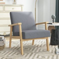 a gray chair sitting on top of a rug in a living room next to a lamp