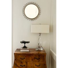 a dresser with a mirror and lamp on it in a white walled room next to a wall