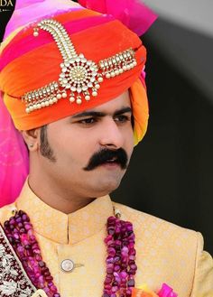 a man in an orange turban is dressed up with beads and jewels on his head