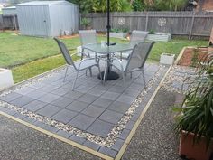 an outdoor patio with table and chairs under an umbrella in the middle of graveled area