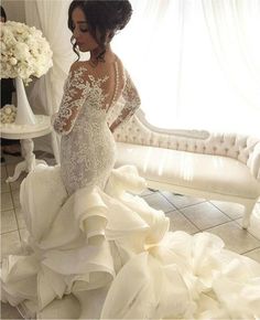 a woman in a white wedding dress standing next to a couch and flower bouquets