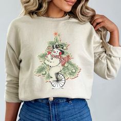 A nostalgic Christmastime sweatshirt featuring a cute snowman in front of a Christmas Tree. These garments are made from polyester and cotton. This combination helps designs come out looking fresh and beautiful. The collar is ribbed knit, so it retains its shape even after washing. There are no itchy side seams on these sweaters.  -50% cotton, 50% polyester -Medium-heavy fabric (8.0 oz/yd² (271.25 g/m -Loose fit -Sewn-in label -Runs true to size. Available in sizes S-2XL -Sweatshirt Brand: Gildan 18000 HOW TO CARE FOR YOUR GARMENT: Wash items inside out in cold water to preserve the print and color longer. Cotton shirts may shrink in the dryer if the heat is set high. Please do not bleach, do not dry clean and do not iron directly on the design. SIZE GUIDANCE: SIZE   Width (inches) Length Christmas Long Sleeve Tops With Cartoon Print, Long Sleeve Cartoon Print T-shirt For Winter, Casual Christmas Sweatshirt With Cartoon Print, Christmas Cotton Sweatshirt With Graphic Print, Vintage Christmas Crew Neck Top, Holiday Cotton Sweatshirt With Graphic Print, Holiday Cotton Sweater With Graphic Print, Holiday Graphic Print Cotton Sweatshirt, Vintage Snowman