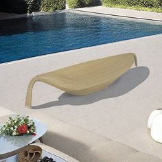 an outdoor lounge chair next to a pool with flowers on the table and in front of it