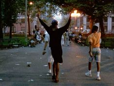 two men are walking down the street with their arms in the air and one man is holding his hands up