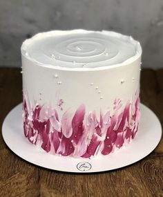 a close up of a cake on a wooden table with white frosting and pink flowers