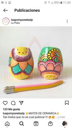 two colorful painted eggs sitting on top of a table next to a pen and marker