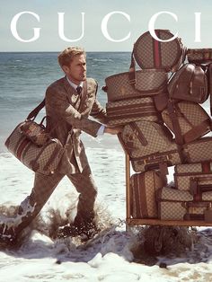 a man carrying luggage on top of a beach next to the ocean with words gucci