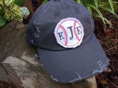 a baseball cap with the letter j t e embroidered on it sitting on a rock