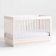 a baby crib with white sheets on the bottom and sides, against a plain background