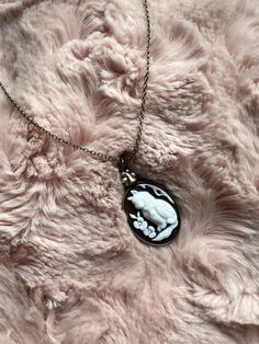 Add a little quirky flair to your elegant style when you wear jewelry from Cosmic Created Magic! Feel as if you've stepped right out of a Victorian fairytale with a lovely vintage inspired cameo cat necklace. The colors of the cameo silhouette are white and dark brown with a slight auburn tone. The silhouette depicts a majestic fluffy kitty cat along with two flowers. At the top of the pendant are four small Pearl colored beads. Dangling from a dainty antique gold necklace. This is a great gift for cat owners and cat lovers. A perfect necklace for cameo jewelry fanatics. Fluffy Kitty, Antique Gold Necklace, Two Flowers, Cameo Jewelry, Cameo Necklace, Cat Necklace, Pearl Color, Cat Owners, Kitty Cat